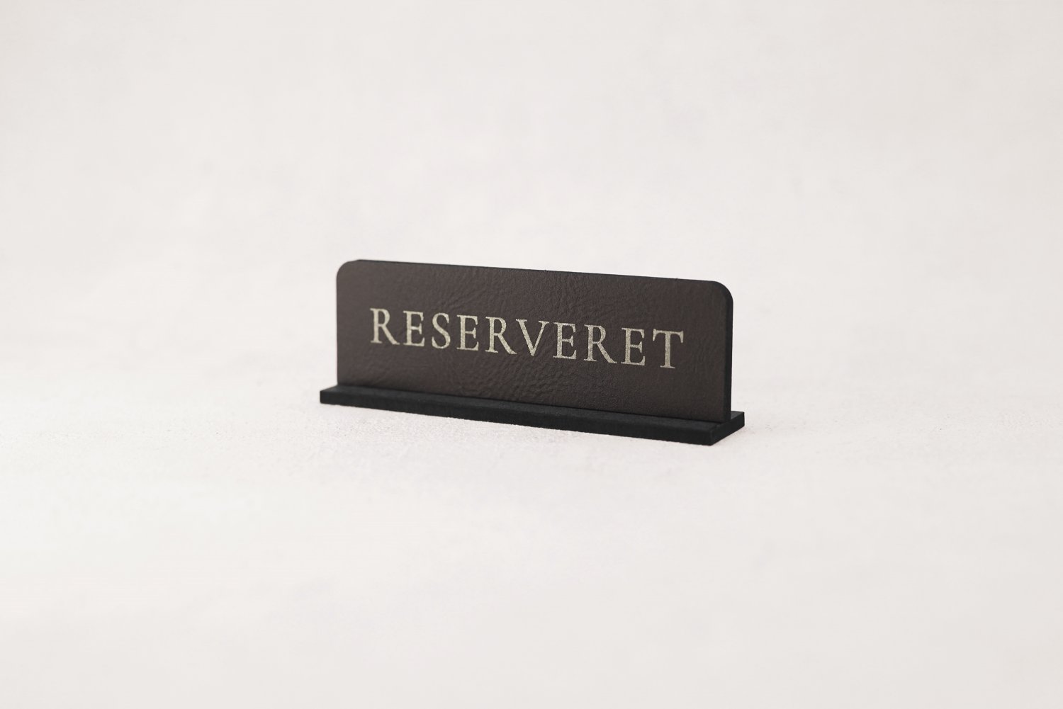 Små reservationskilte i læder til restaurant med sølvskrift